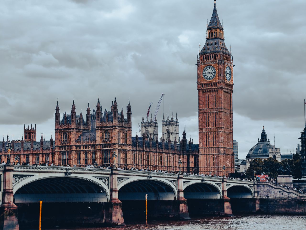 Services Dramatic view of Big Ben and Westminster Bridge against cloudy skies in London.